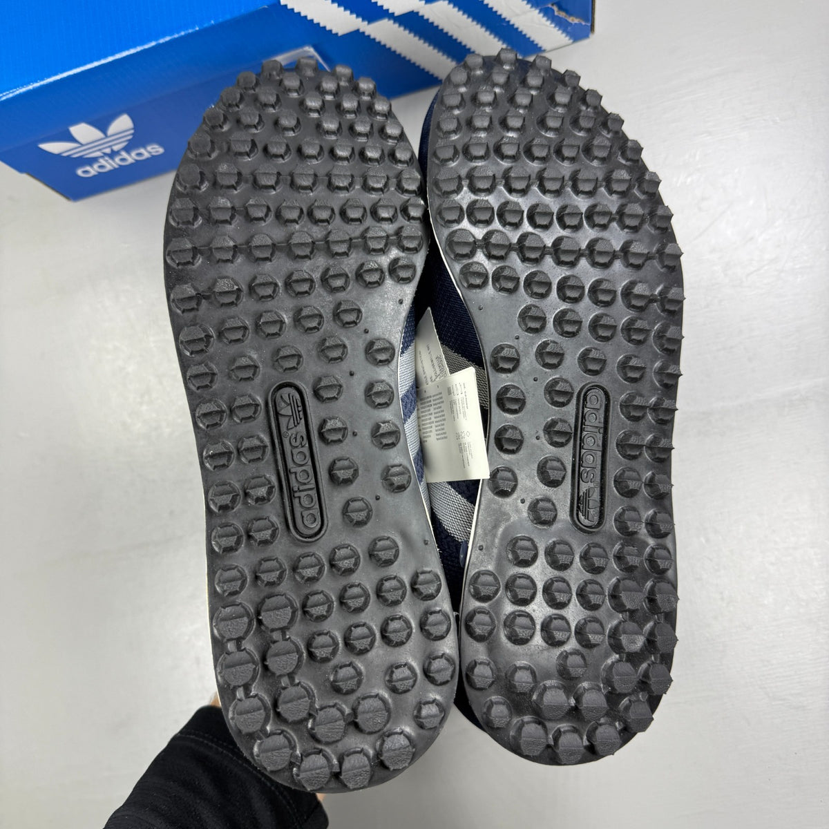 Adidas blue athletic shoes with white accents and textured weave design.