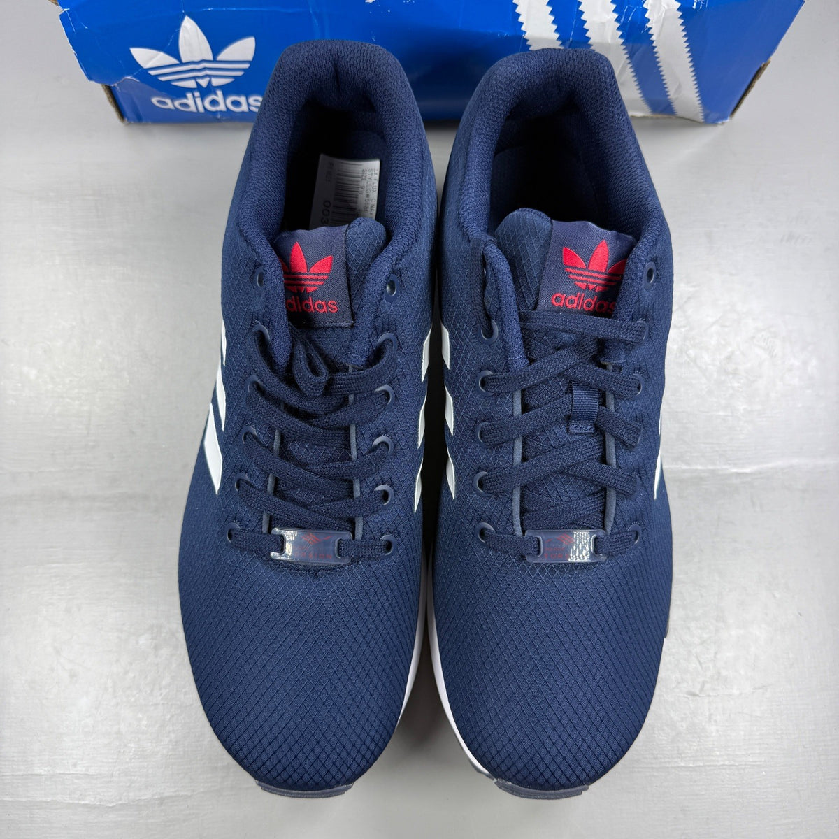 Adidas blue athletic shoes with white accents and ZX Flux logo details.
