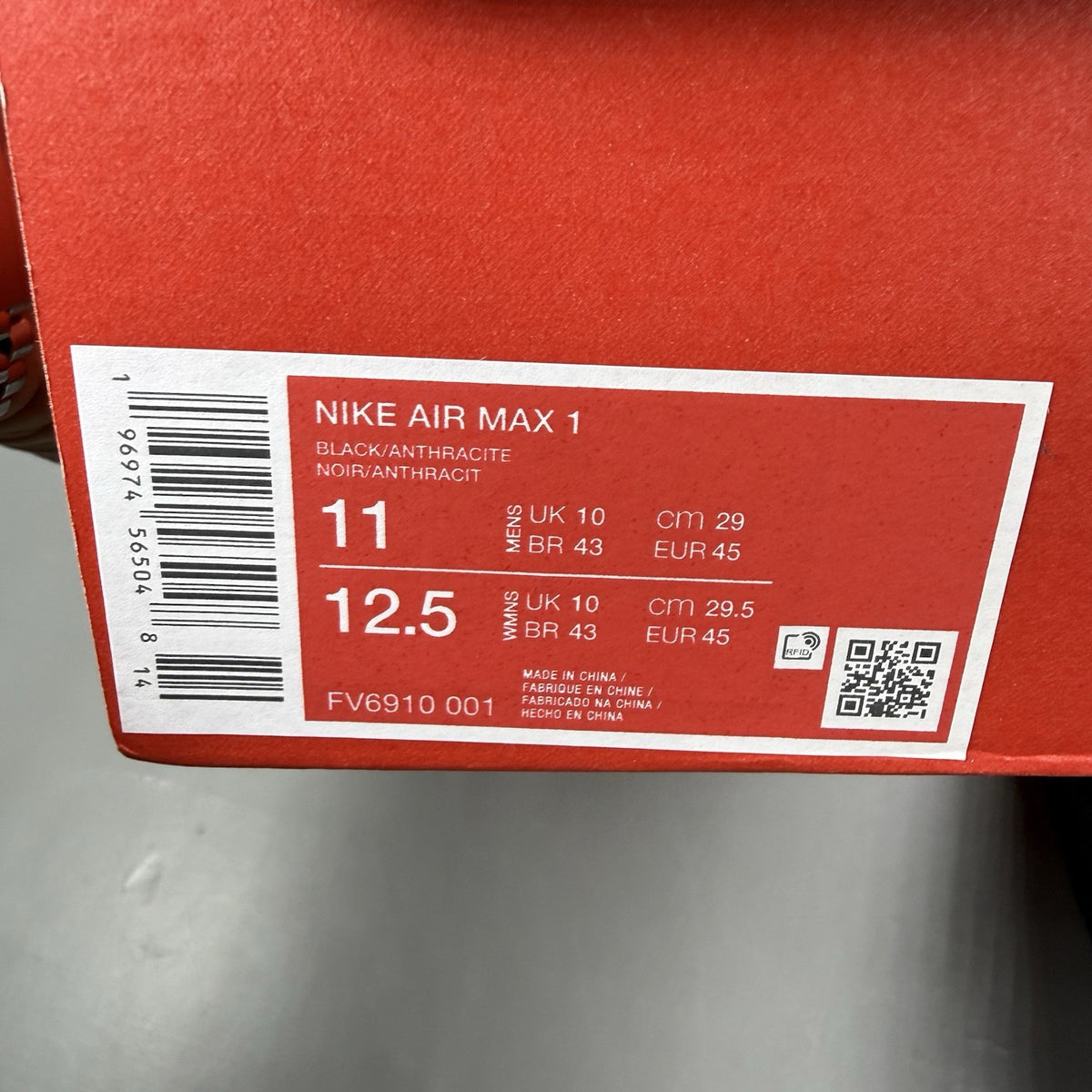 Nike Air Max 1 trainers black with red accents and logo detail on the side.