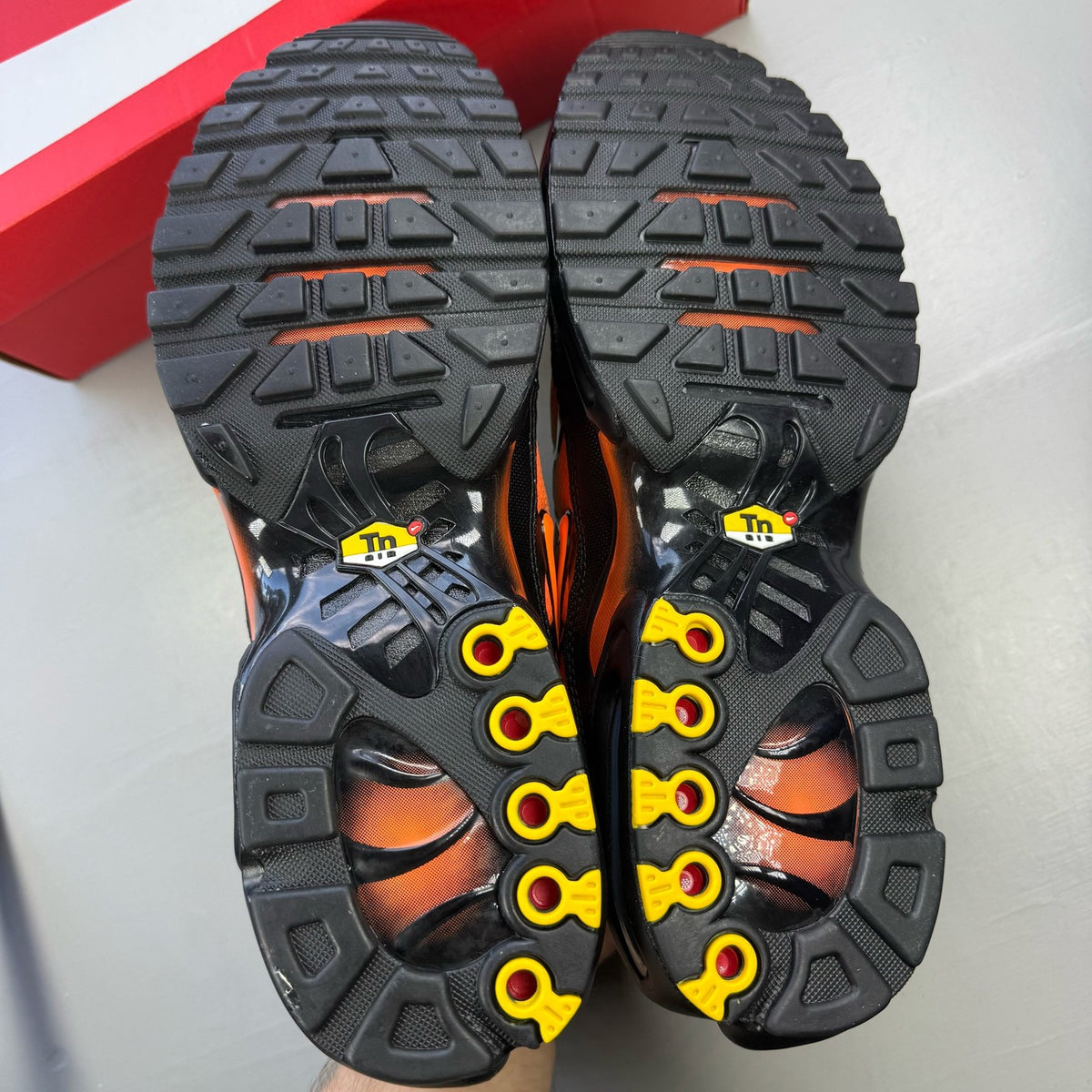 Nike Air Max Plus TN black trainers with total orange accents and signature logo.