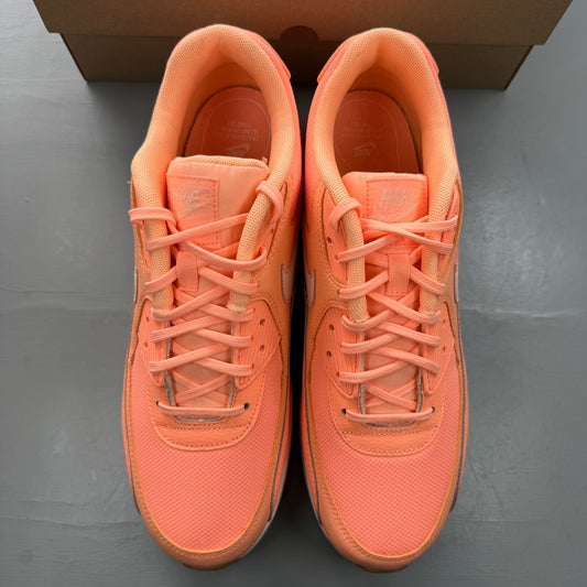 Nike Air Max 90 orange trainers with white accents and gum sole, featuring logo detail.