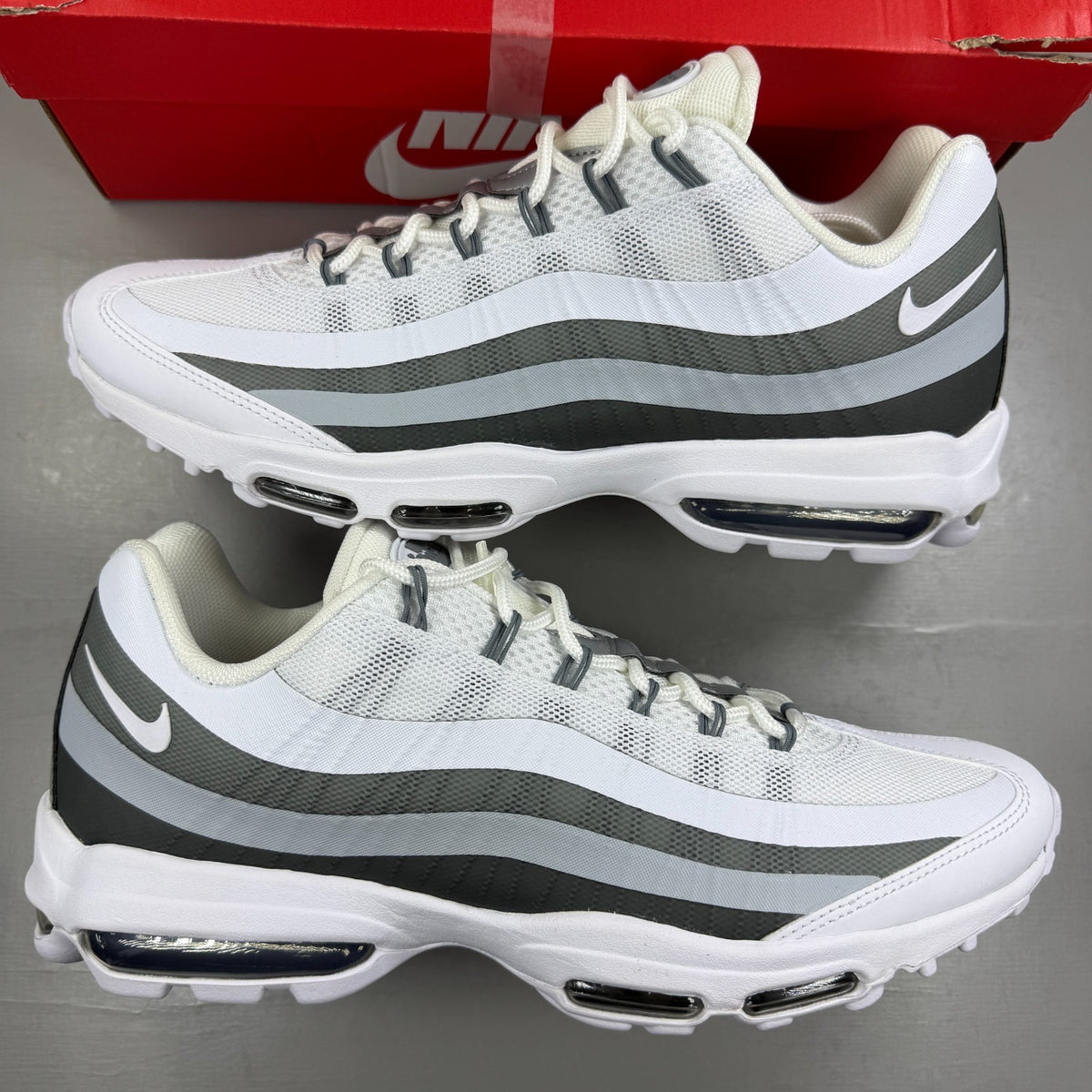 Nike running shoes white with grey accents and Air Max cushioning design.