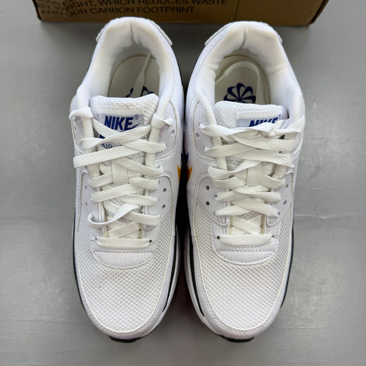 Nike Air Max 90 white athletic shoes featuring double swoosh logo and sleek design.