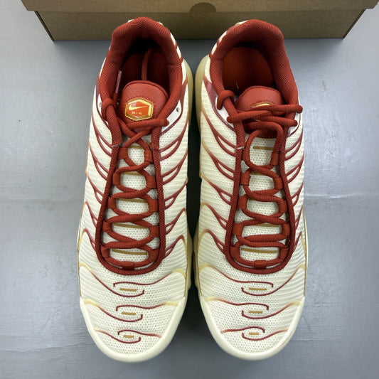 Nike Air Max Plus TN gold trainers with red accents and signature logo detailing.