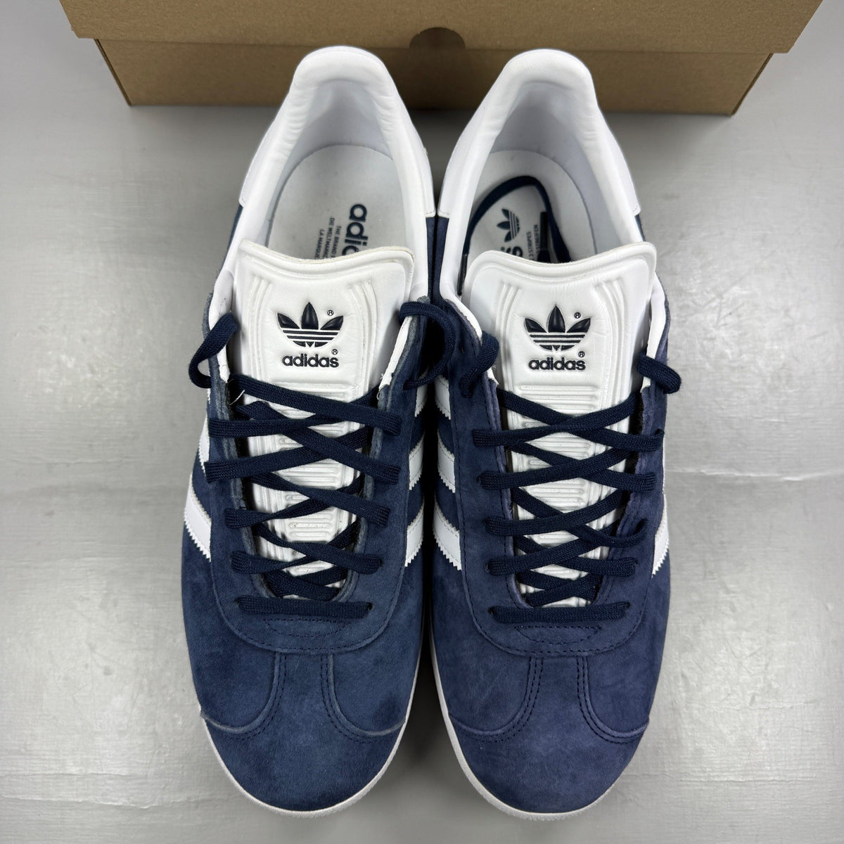 Adidas blue suede trainers with white stripes and logo detailing.