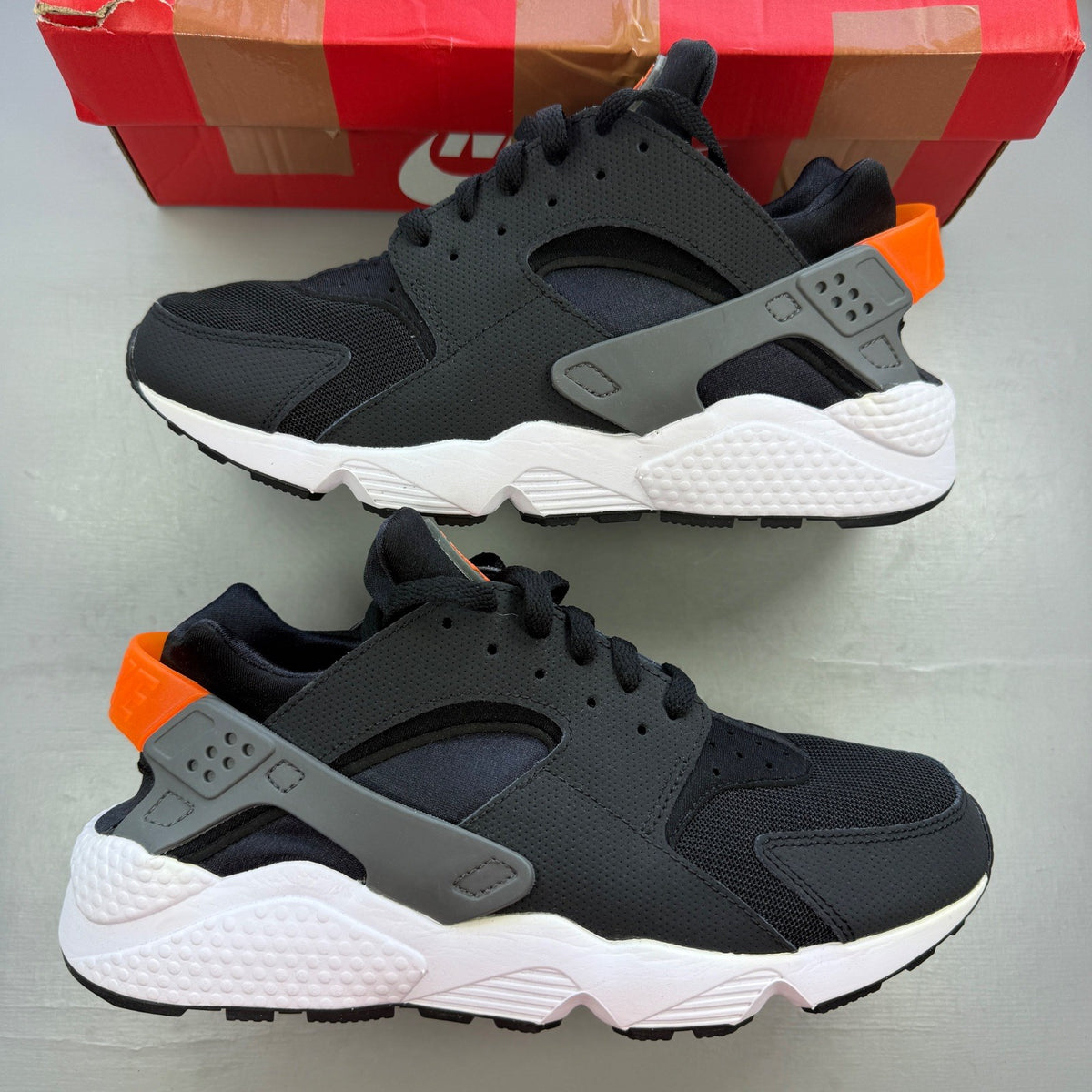 Nike black athletic shoes with safety orange accents and grey detailing.
