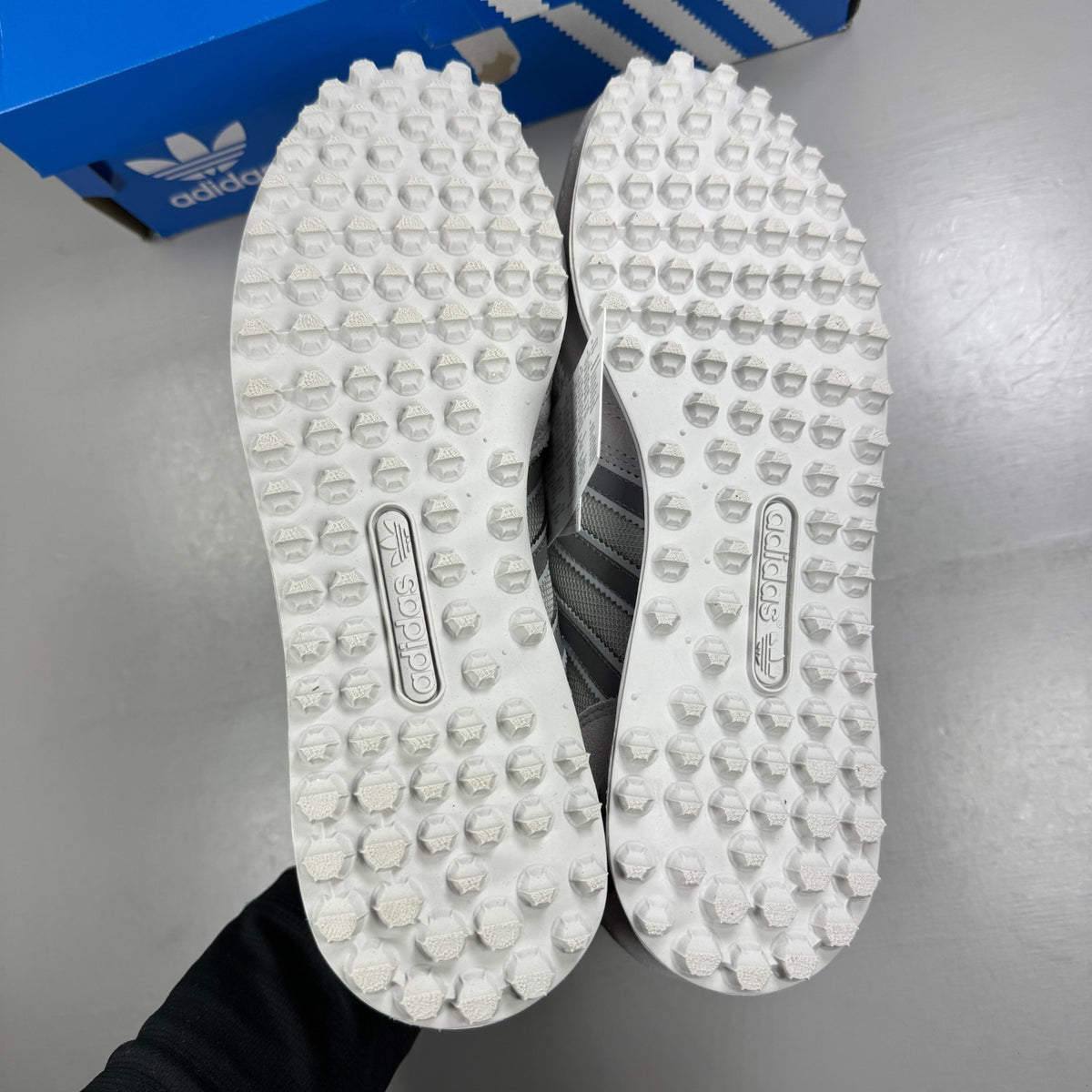 Adidas grey athletic shoes with white accents and classic three-stripe logo.