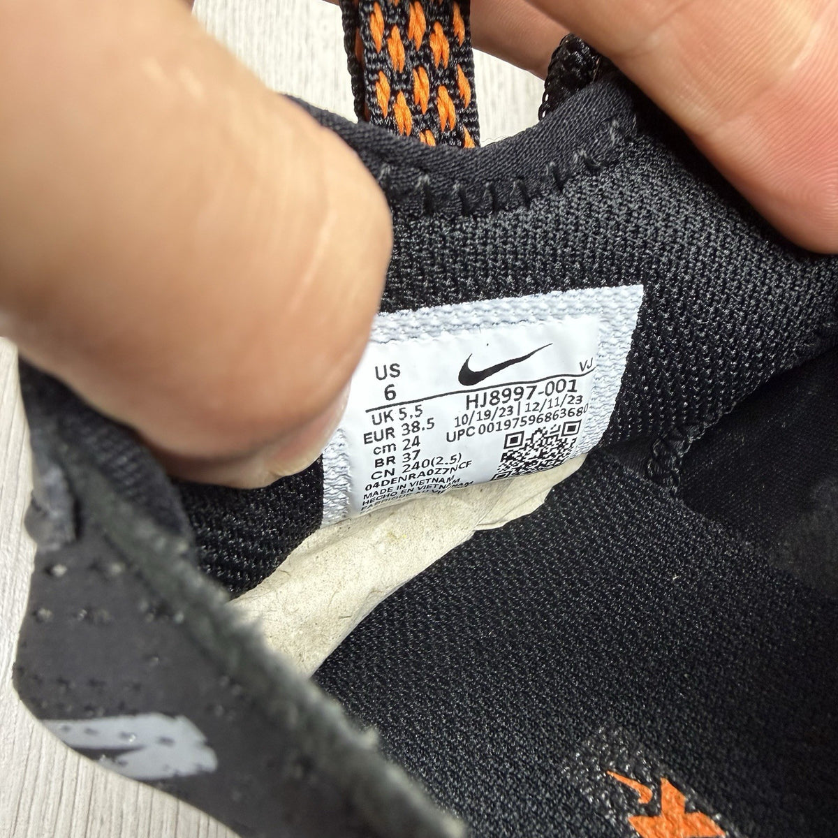 Nike React Vision black trainers with safety orange accents and unique design details.