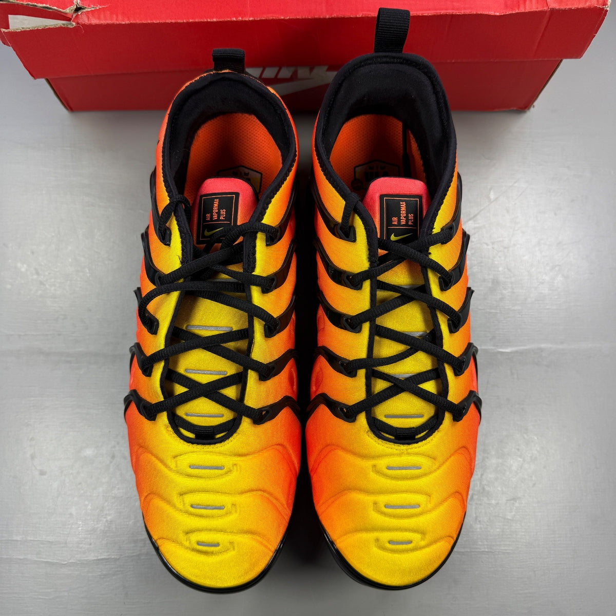 Nike athletic shoes orange with black accents and Air VaporMax sole design.