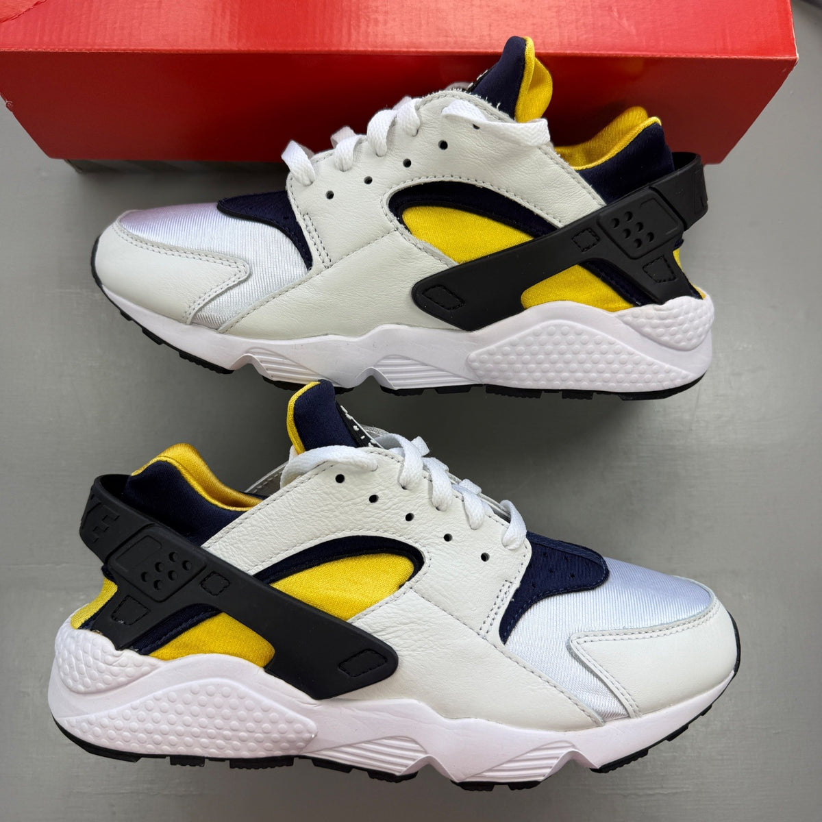 Nike athletic shoes white with yellow maize and navy accents, featuring iconic Huarache design.