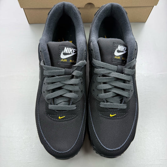 Nike Air Max 90 black trainers with speed yellow and gold accents, mesh and leather material.