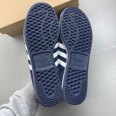 Adidas Originals navy suede trainers with white stripes and logo detailing.