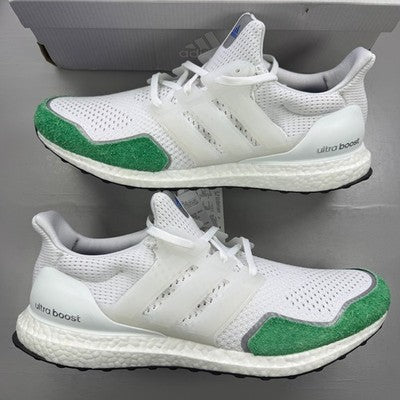 Adidas white trainers with green accents and Boost cushioning technology.
