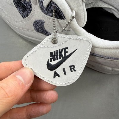 Nike trainers white with black snakeskin pattern and logo detail.