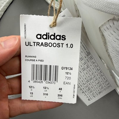 Adidas white trainers with green accents and Boost cushioning technology.