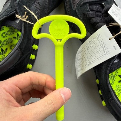 Adidas Originals black and yellow trainers with iconic three stripes and cushioned sole.