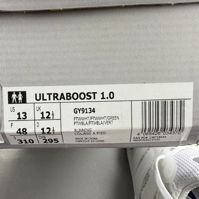 Adidas white trainers with green accents and Boost cushioning technology.