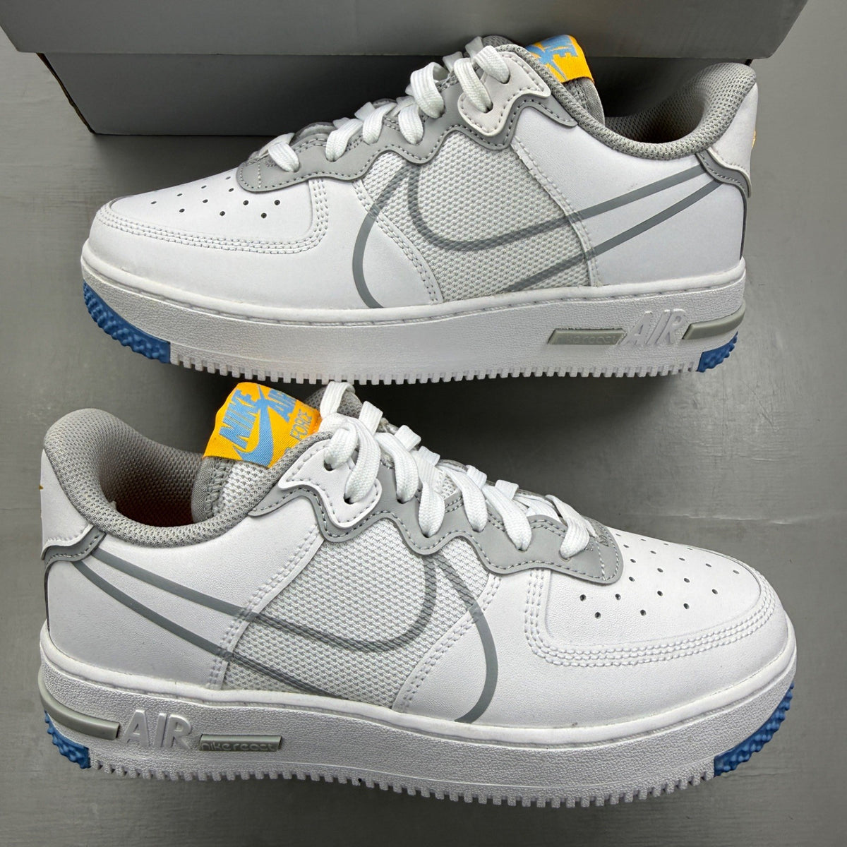 Nike Air Force 1 React white trainers with smoke grey accents and logo details.