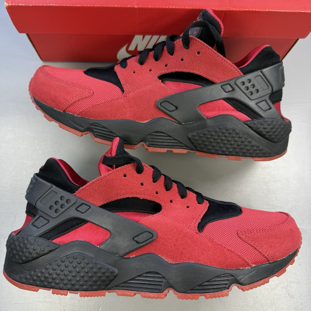 Nike Air Huarache trainers red and black with distinctive logo and unique design details.