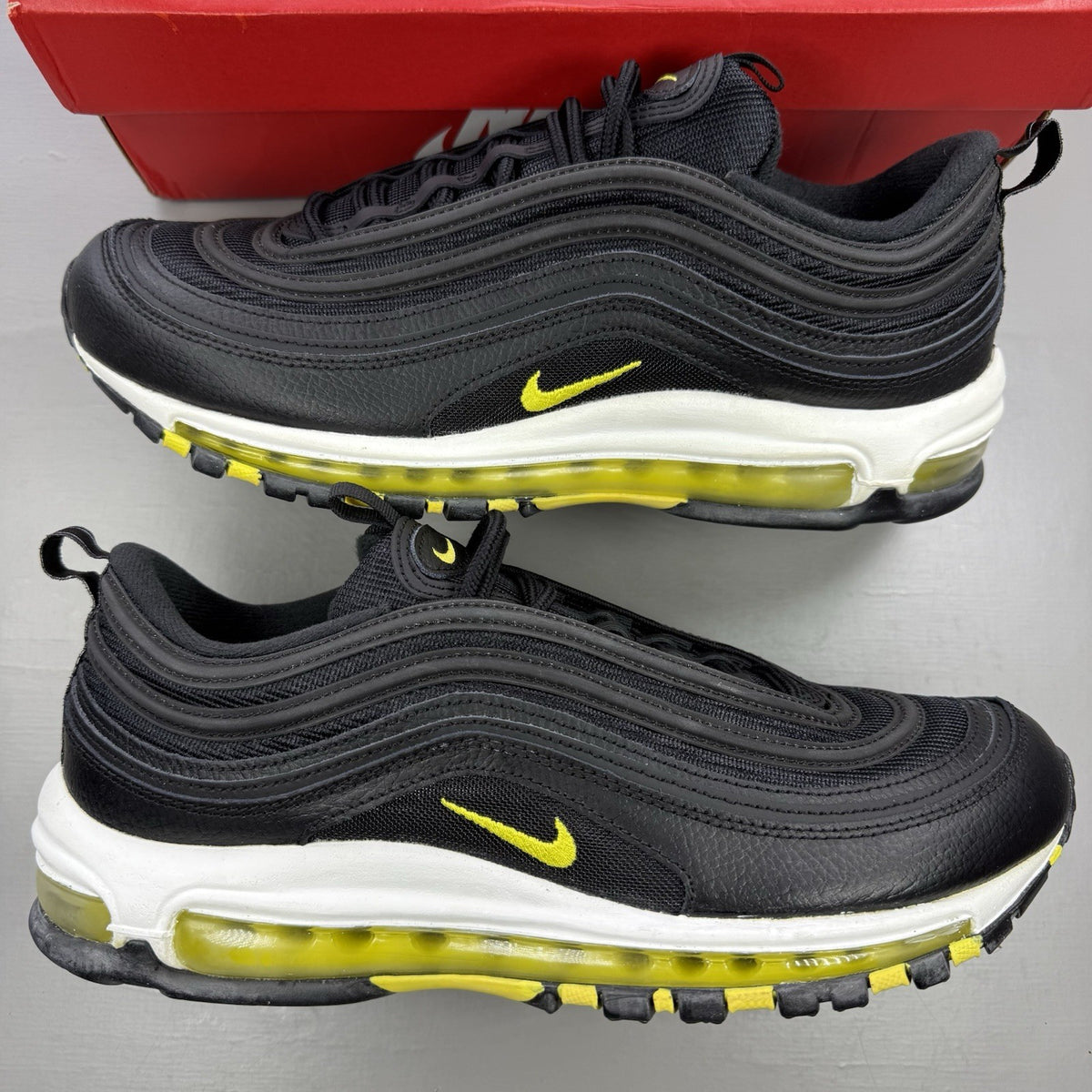 Nike Air Max 97 black trainers with opti yellow accents and white sole.
