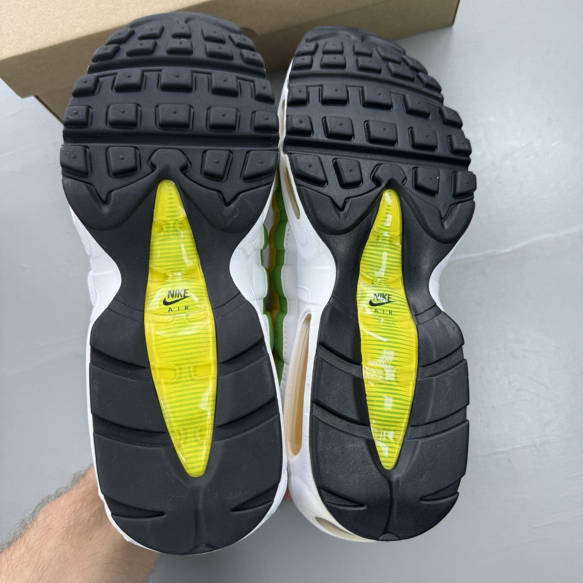 Nike Air Max 95 white trainers with green and yellow accents, featuring iconic logo details.