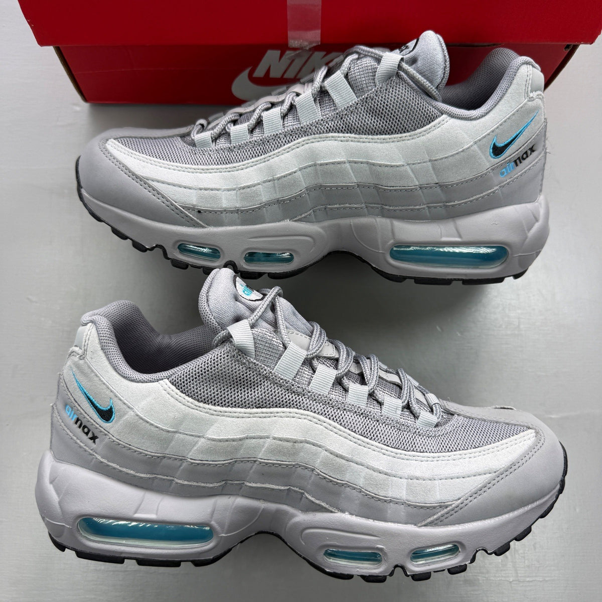 Nike trainers grey with aqua accents and retro logo detailing.