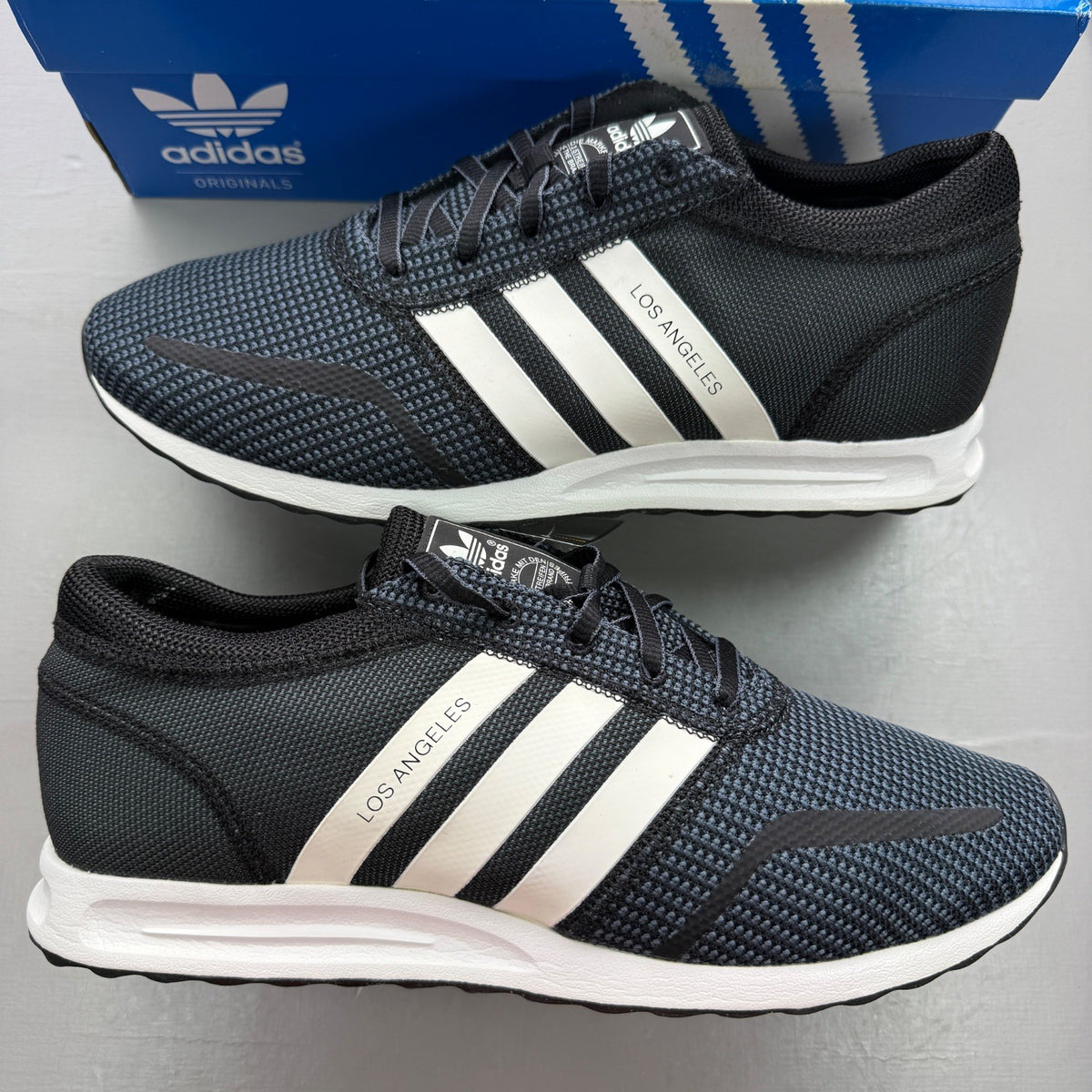 Adidas black deck shoes with white stripes and logo, brand new in box.