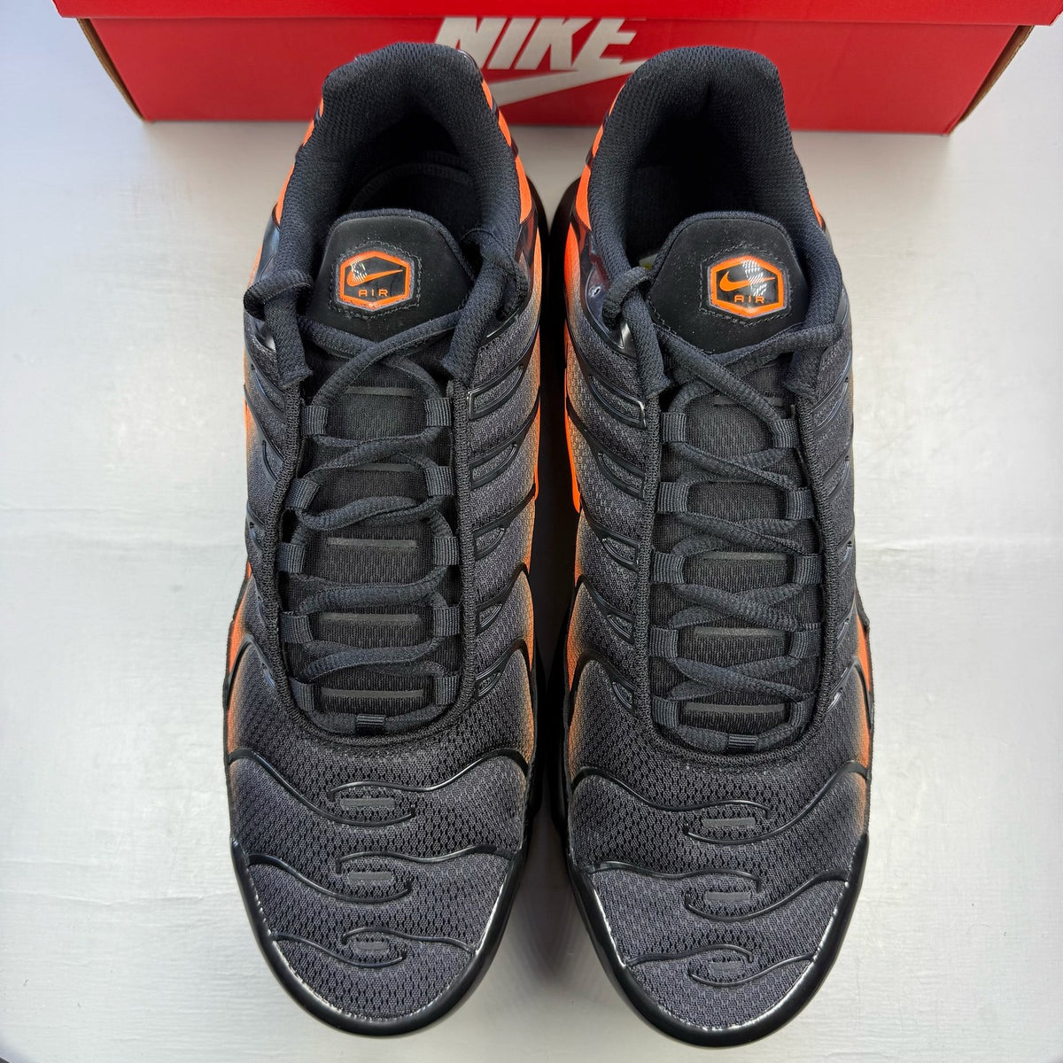 Nike Air Max Plus TN black trainers with total orange accents and signature logo.