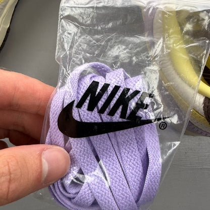 Nike Dunk Low purple trainers with soft yellow accents and classic swoosh logo.