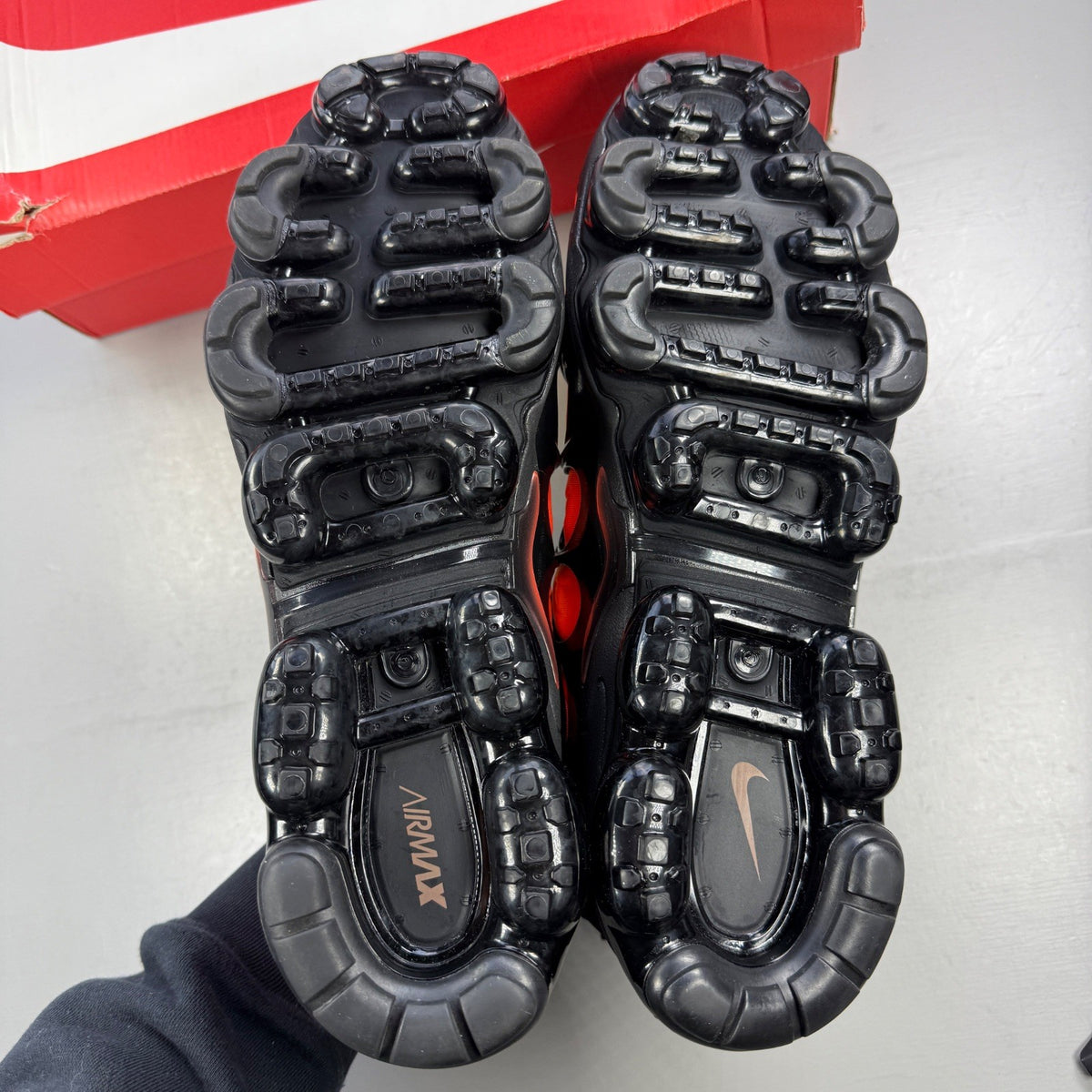 Nike athletic shoes orange with black accents and Air VaporMax sole design.