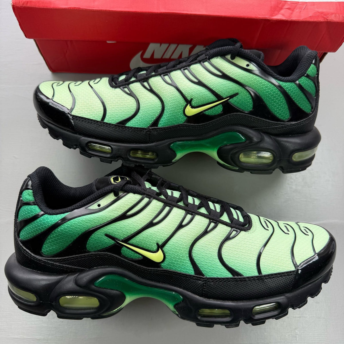 Nike Air Max Plus TN green trainers with lemon twist accents and signature logo.