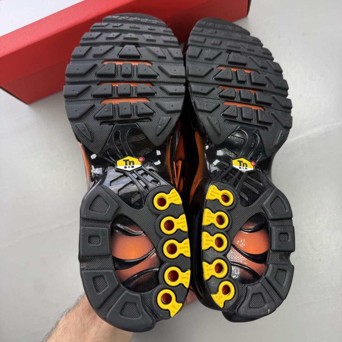 Nike Air Max Plus TN black trainers with total orange accents and signature logo.