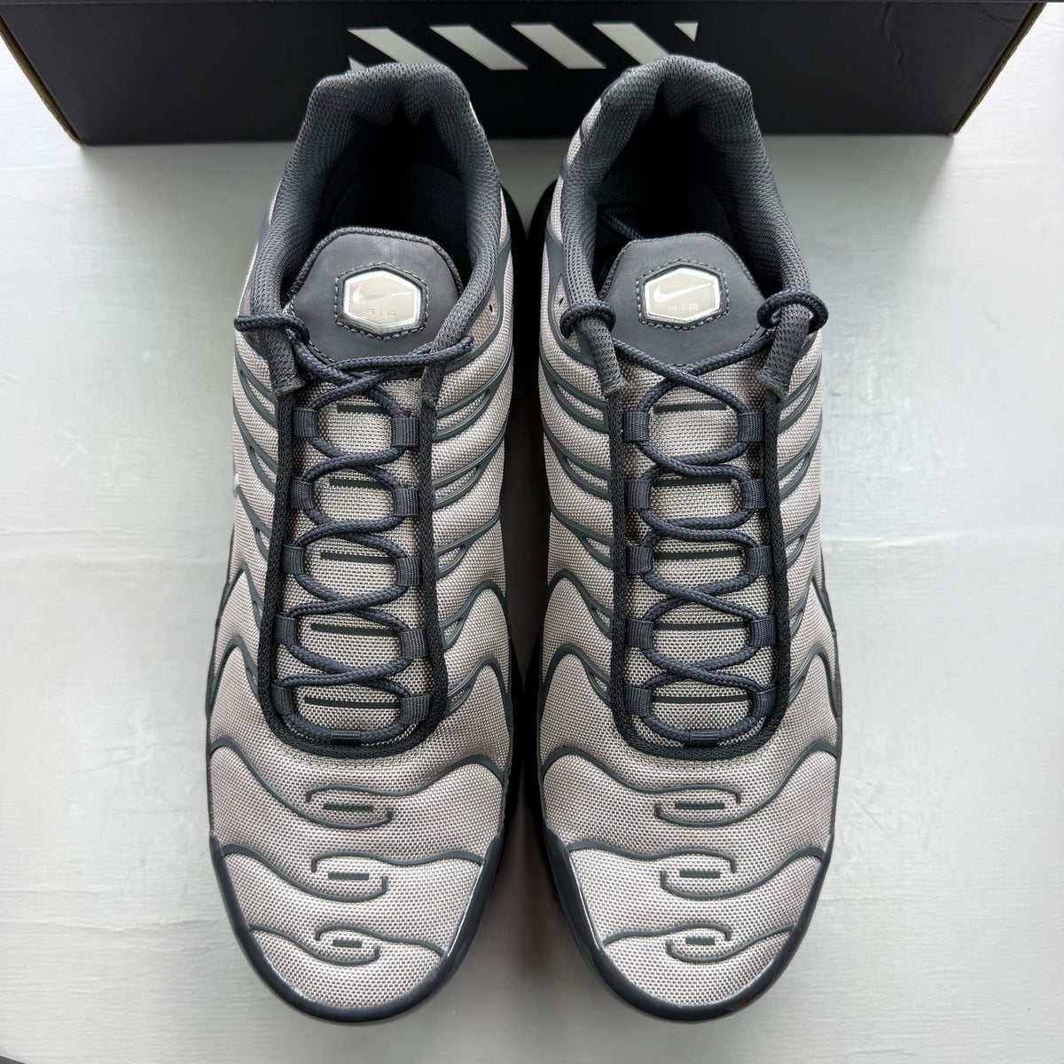 Nike black trainers with dark smoke grey accents and signature Air Max Plus design.