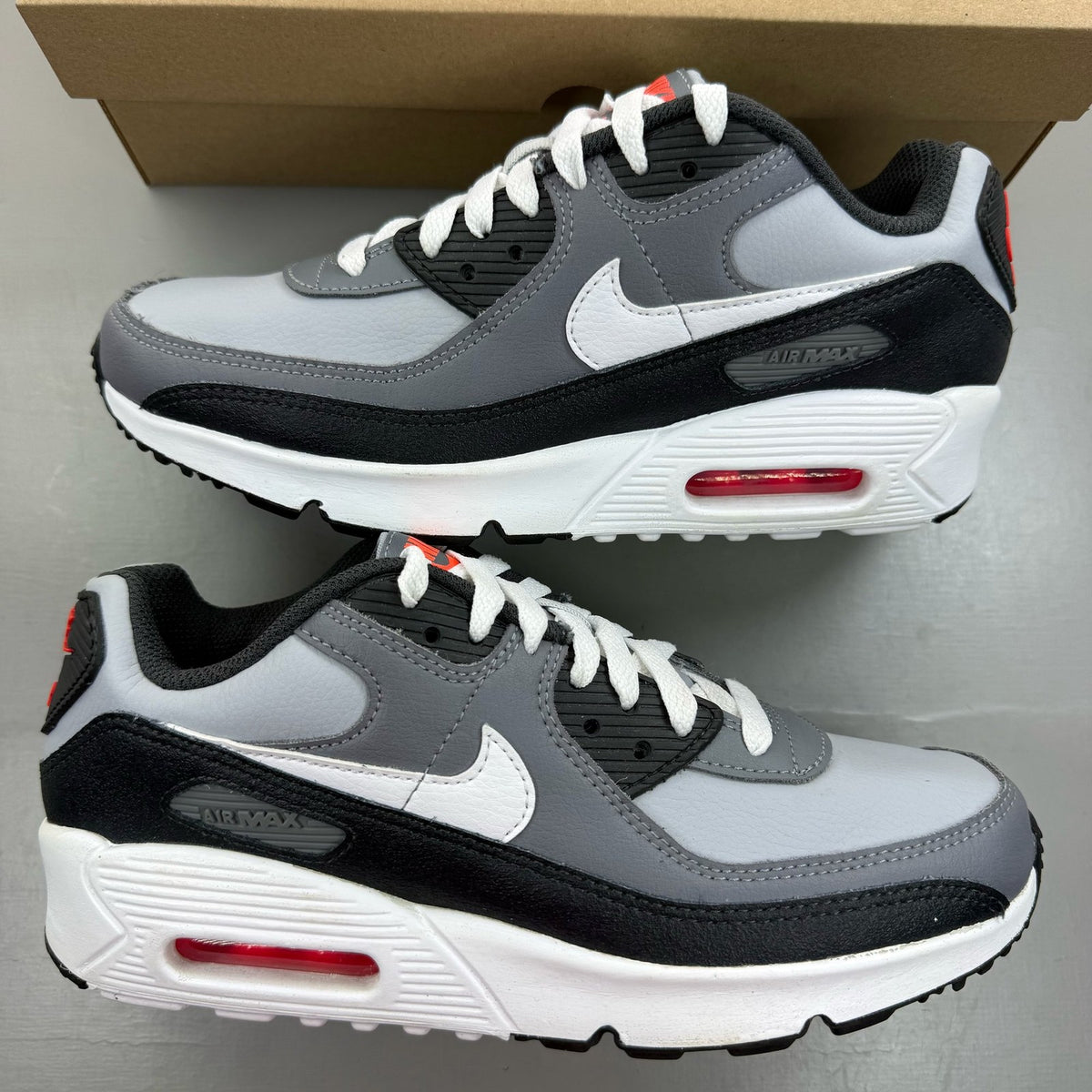 Nike Air Max 90 grey trainers with leather upper and signature swoosh logo.