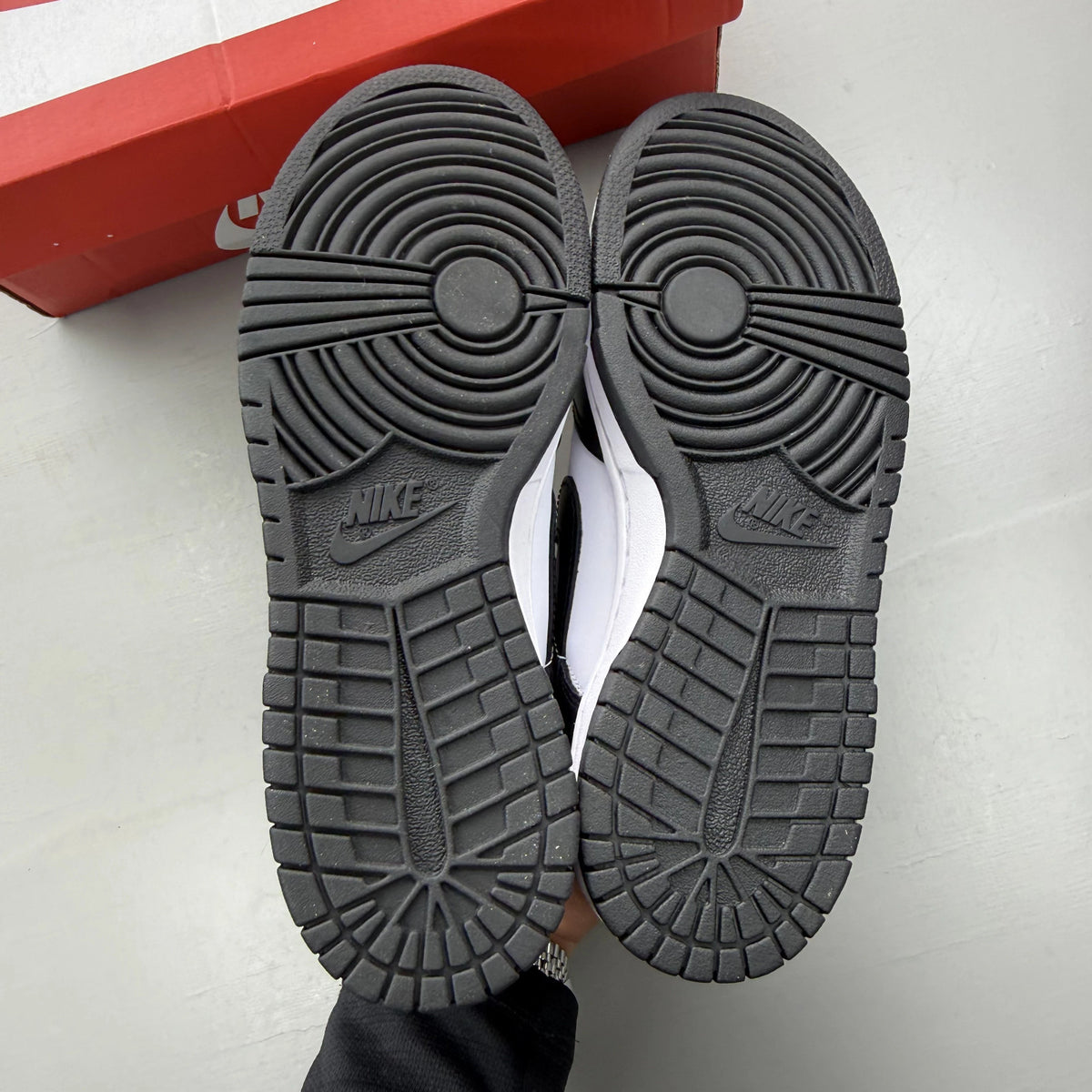Nike Dunk Low white and black sneakers with retro panda design and logo.