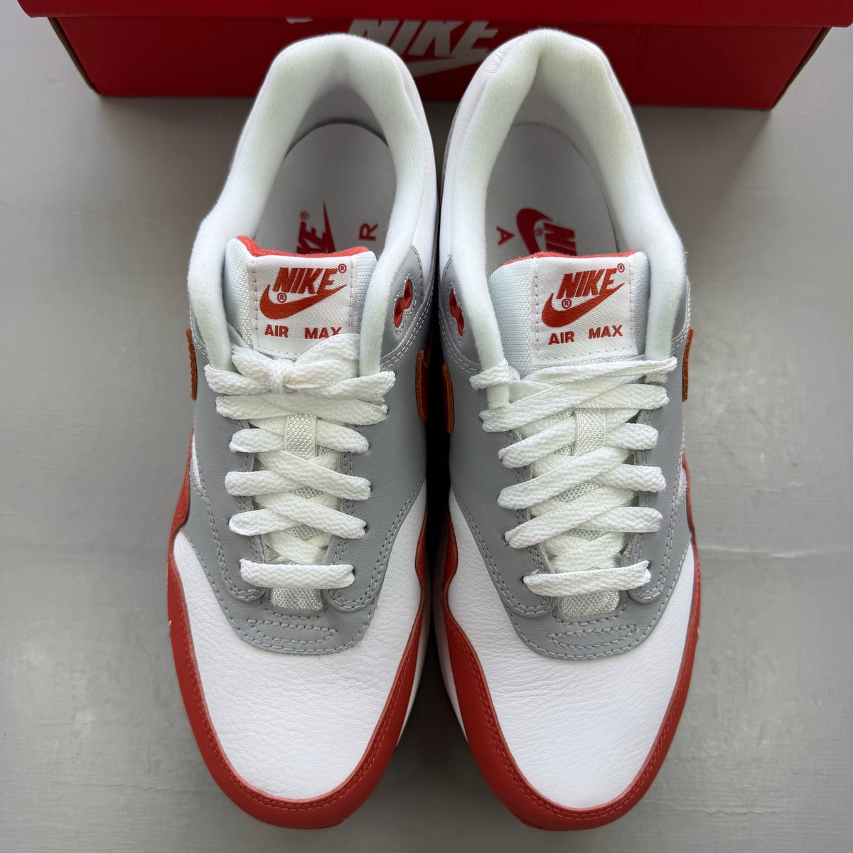 Nike Air Max 1 white trainers with grey accents and Martian Sunrise detailing.
