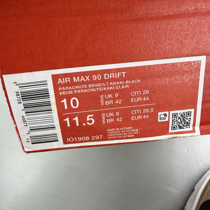 Nike Air Max 90 Drift beige trainers with black and white accents, featuring logo details.