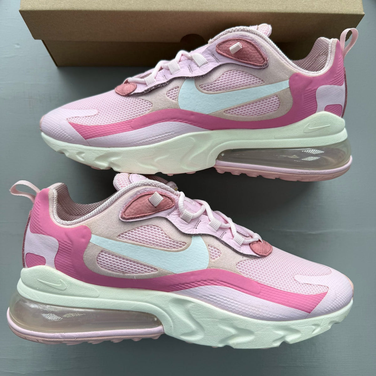 Nike Air Max 270 React white trainers with pink accents and logo detail.