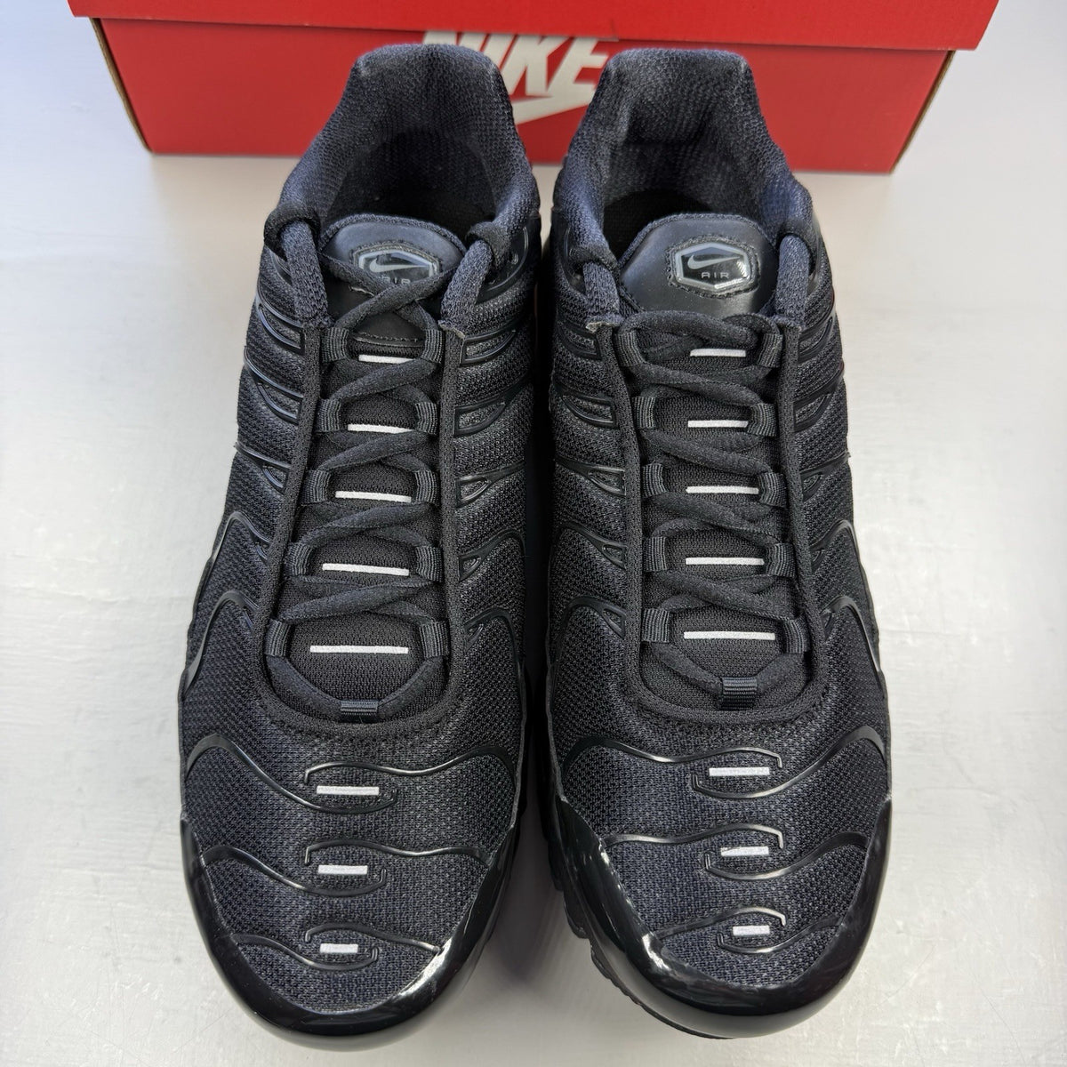 Nike Air Max Plus TN black trainers featuring distinctive wavy design and cushioned sole.