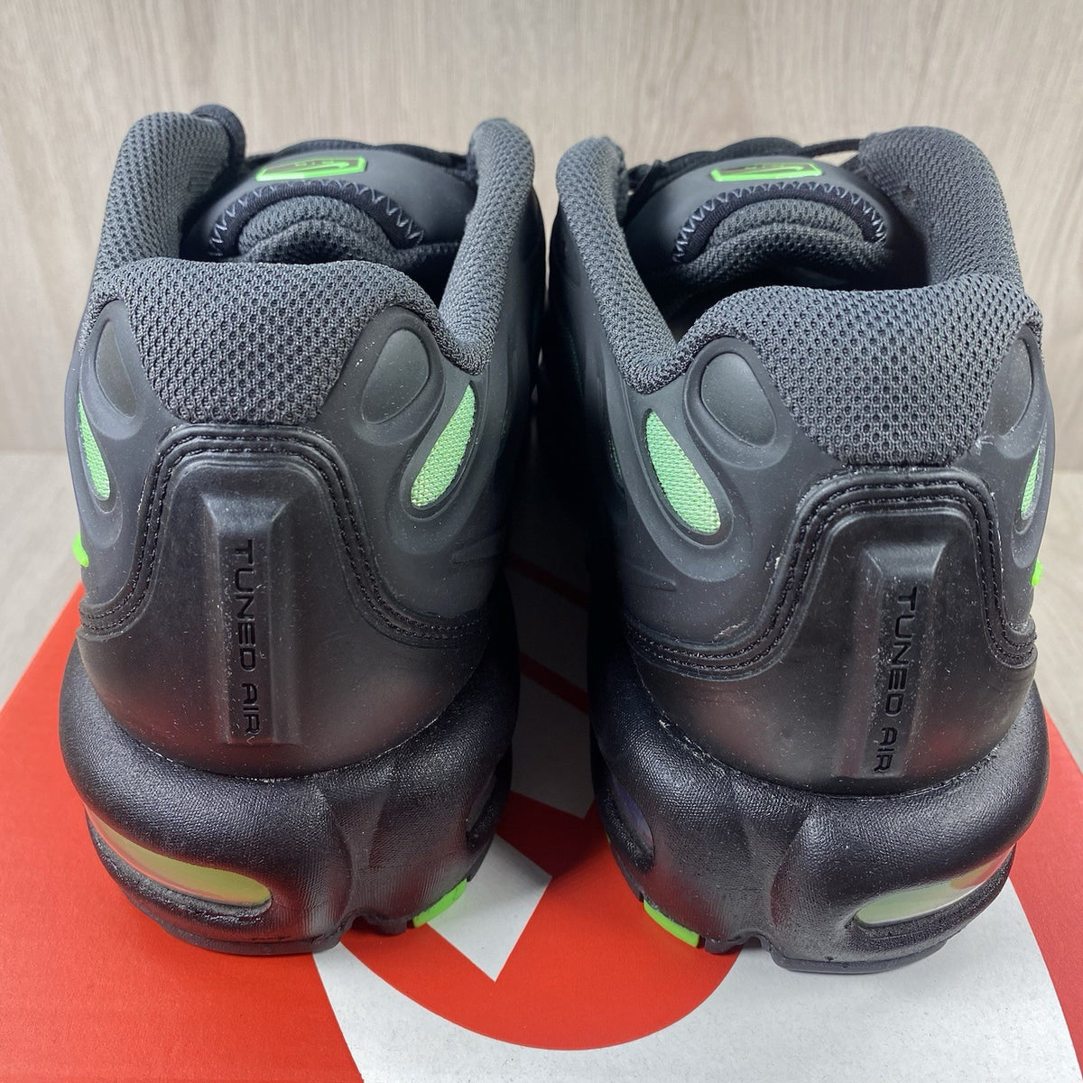 Nike Air Max Plus trainers black with volt green accents and signature swoosh logo.