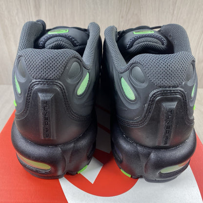 Nike Air Max Plus trainers black with volt green accents and signature swoosh logo.