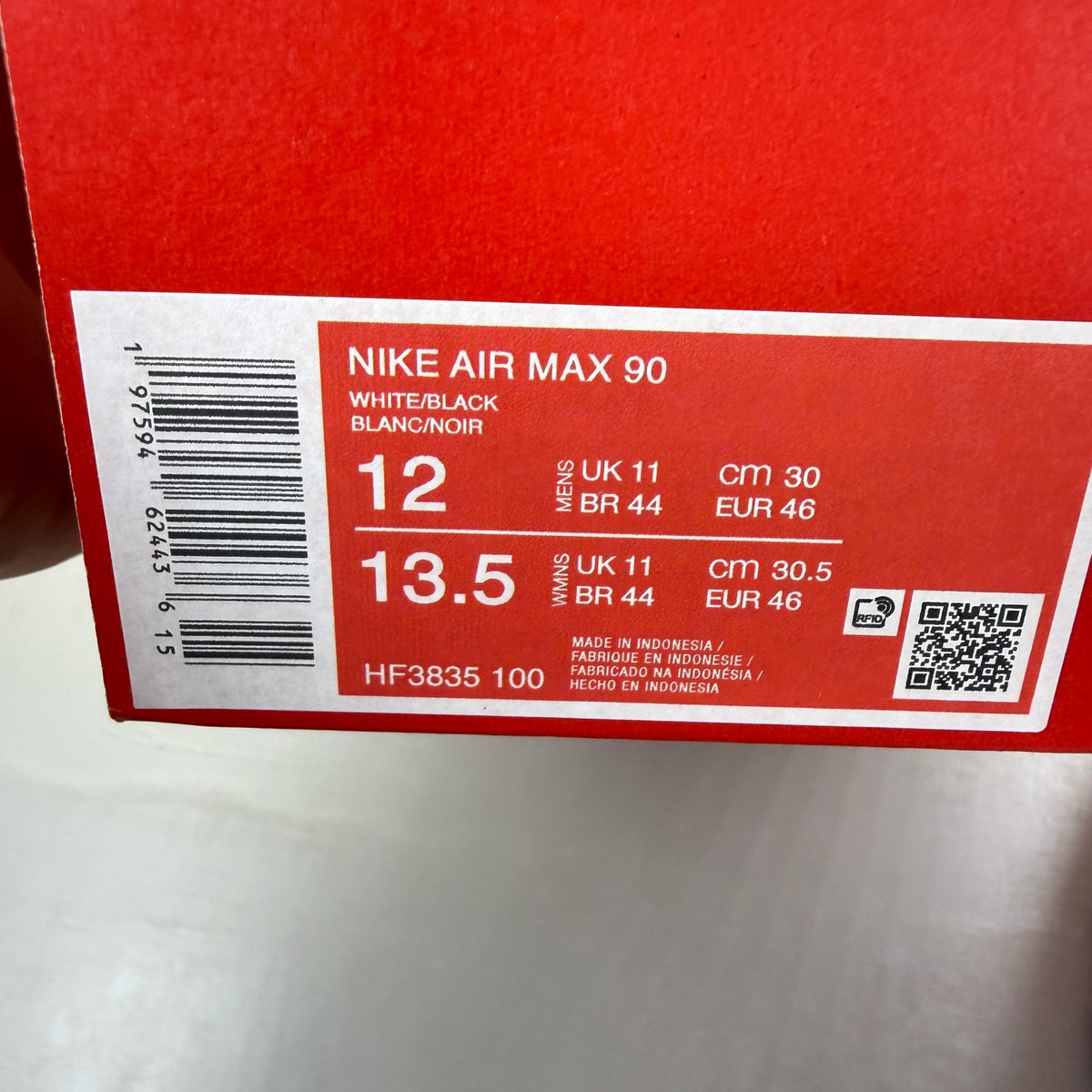 Nike Air Max 90 white trainers with black outlined swoosh logo and mesh material.