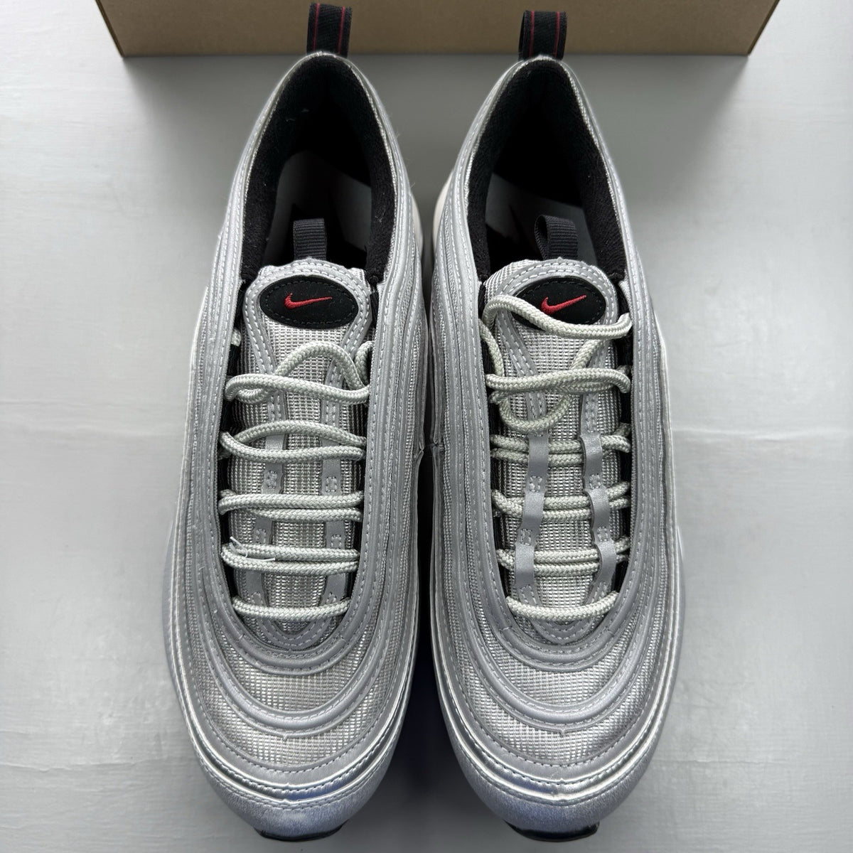 Nike Air Max 97 silver trainers with metallic finish and signature swoosh logo.