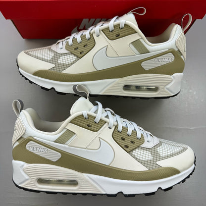 Nike Air Max 90 beige trainers with swoosh logo and mesh detailing.