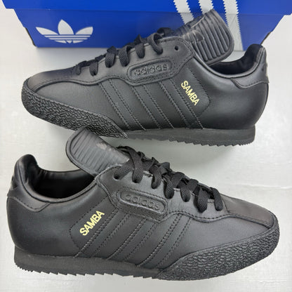 Adidas Samba Super black trainers with white and gold logo detailing.