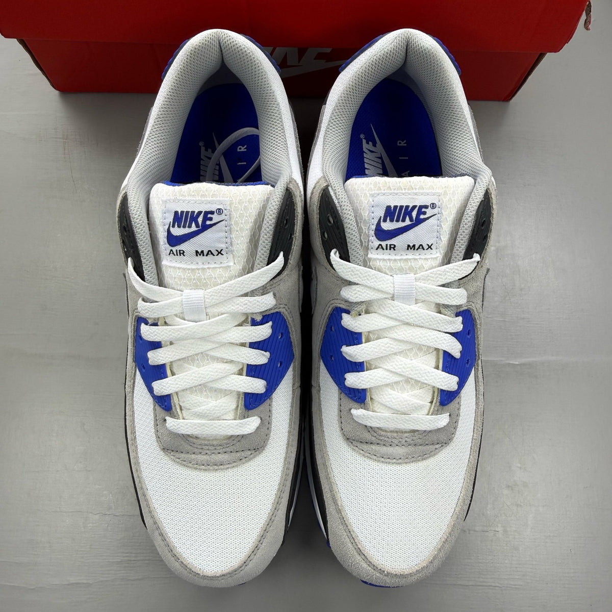 Nike Air Max 90 white trainers with hyper royal blue and grey accents.