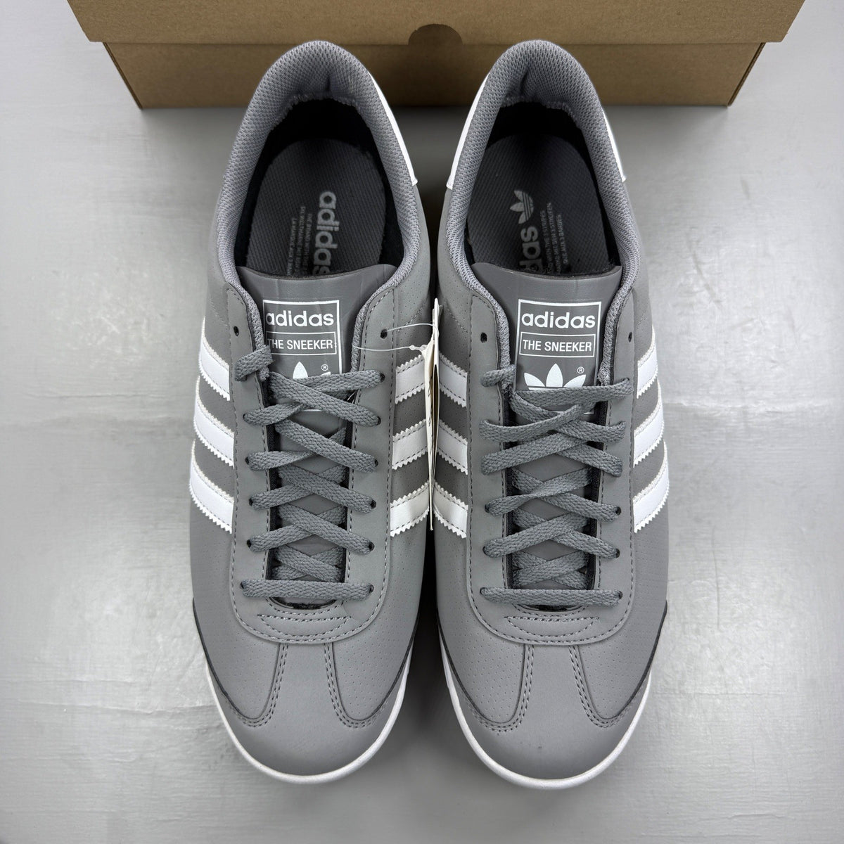 Adidas grey deck shoes with white accents and classic logo detailing.