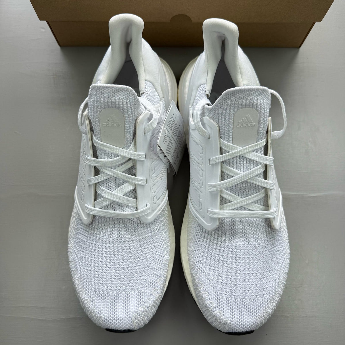 Adidas Ultra Boost 20 white running trainers with mesh upper and signature three stripes.
