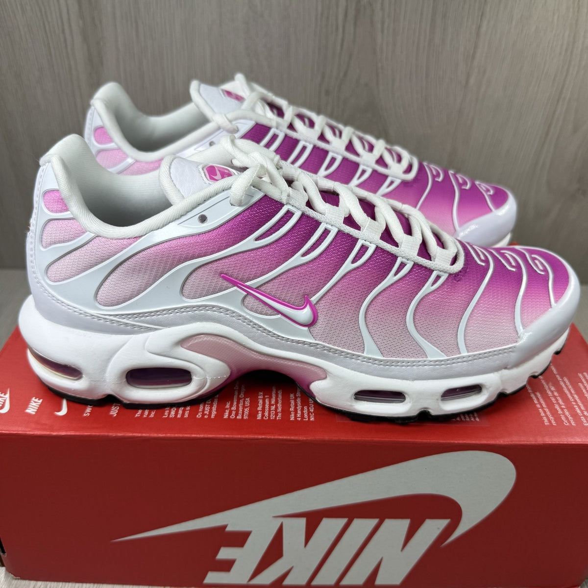 Nike Air Max Plus TN white trainers with fire pink foam fade and logo detailing.