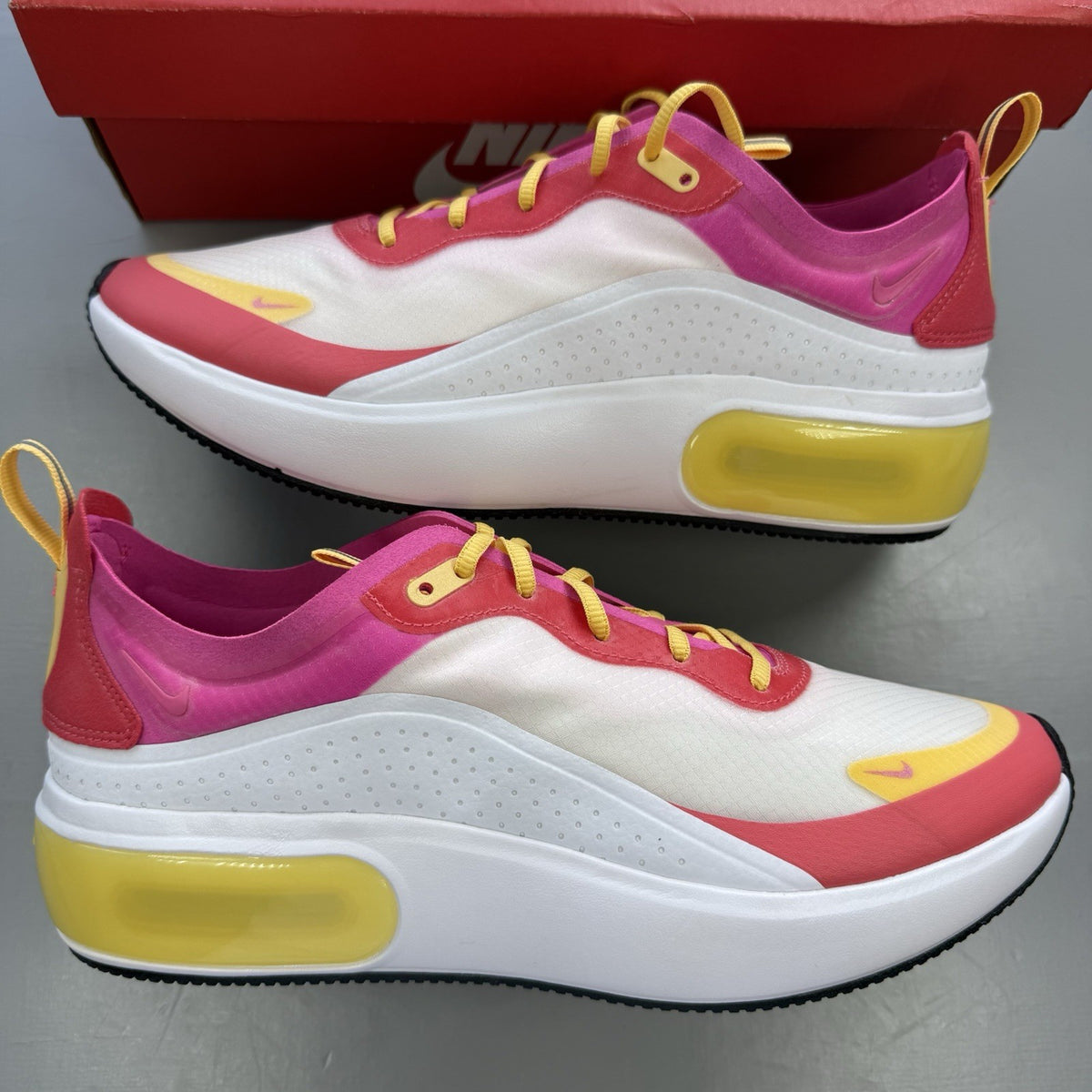 Nike Air Max Dia SE white trainers with laser fuchsia and gold accents, sleek design.